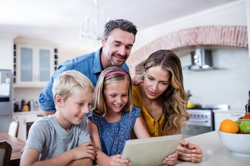 Parents and kids using digital tablet in kitchen