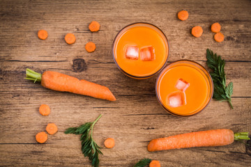 Carrot juice and carrot segments on a wooden background