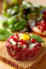 Beef tartare served on a wooden board, close up