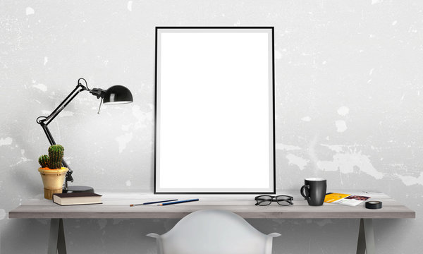 Isolated poster frame on office desk for mockup. Lamp, cactus, pencils, glasses, book, cup of coffee on table.