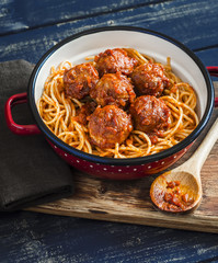 Spaghetti and meatballs in tomato sauce on wooden rustic board. Delicious lunch