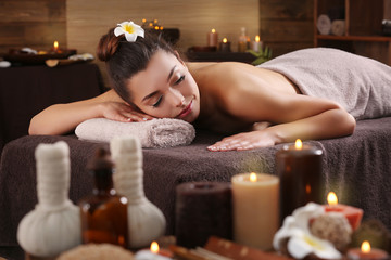 Beautiful young girl with towel lying on massage table in spa salon
