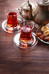 Black tea in glass cups and eastern sweets on wooden table
