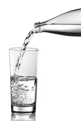 Pouring water from bottle into glass over grey background