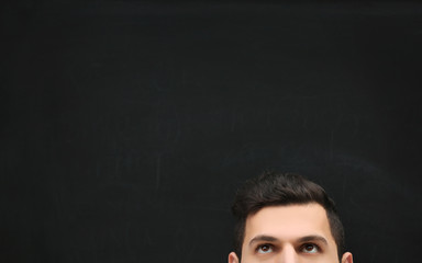 Forehead of a young man against blackboard.