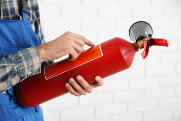 Man hands holding fire extinguisher on white brick wall background