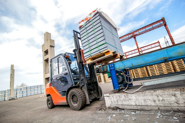 Auto loader with concrete blocks near house-building factory