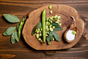 Fresh Broad Beans / Fresh green beans seen from above on a rough wood floor brown color. Seasonings of Mediterranean cuisine: olive oil, salt.