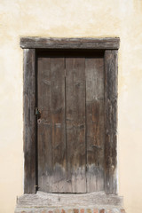 Big wooden old door. Historical house door, one timber leaf, closed brown gateway with planks and nails. Exterior country situation. Rural entry architecture element. Village foundation background.