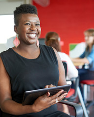 Confident female designer working on a digital tablet in red creative office space © AYAimages