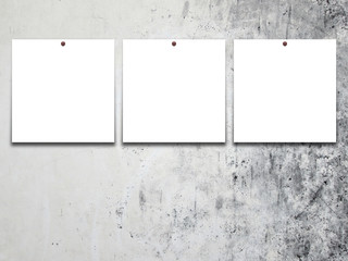 Close-up of three square blank frames with pins on grey concrete wall background