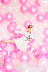 little girl playing with pink balloons