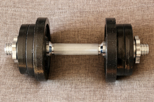 Iron dumbbells on sack cloth background. Weightlifting training concept.