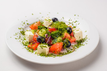 Greek salad in a plate on a white background
