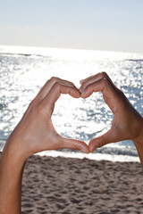mains qui forment un coeur au bord de la mer