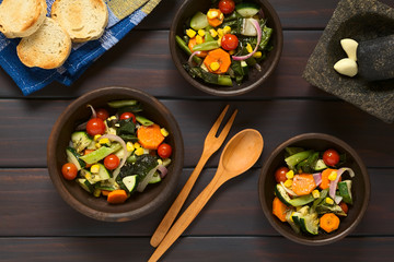 Baked vegetables (zucchini, onion, cherry tomato, broccoli, carrot, sweet corn, green bean, chard) seasoned with thyme, photographed on dark wood with natural light