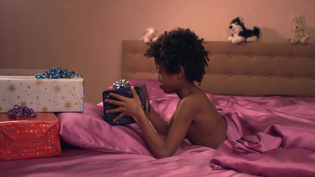 Dark-skinned little boy rejoices of gifts.