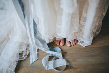 girl in a white wedding dress with blue ribbon standing barefoot on a vintage wooden floor boards of the