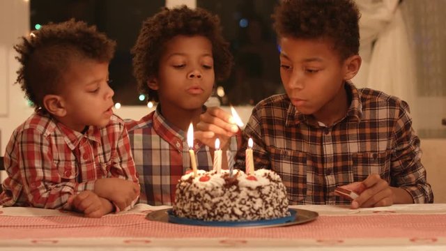 Kids lighting birthday cake's candles.