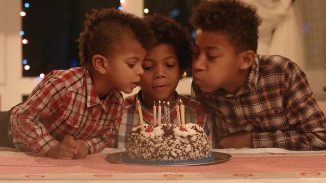 Boy blows out the candles and make a wish.
