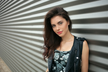 Closeup portrait of young fashionable brunette woman in black leather jacket posing outdoors...