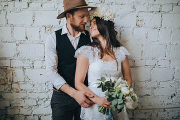 girl with a wreath of white flowers on the head in a white wedding dress and a bearded man in a...