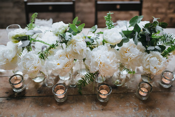 decorated with candles, flowers and bottles of table standing in the loft with white brick walls...