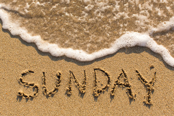 Week series - SUNDAY - written on a sandy beach with the soft wave at sunny day.