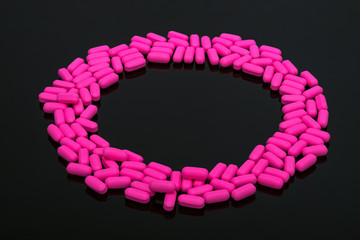 Pills, vitamins on black background, in circle