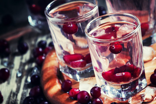 Homemade cranberry vodka, dark wooden background, selective focu