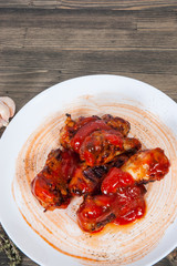 Chicken wings in red tomato sauce on wooden table