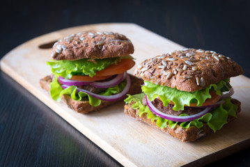 fresh home made burgers with grain bread on wooden background