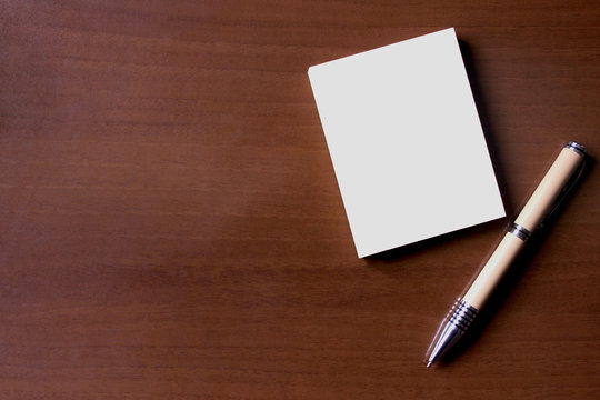 Pen and Notepad on the wooden desk.