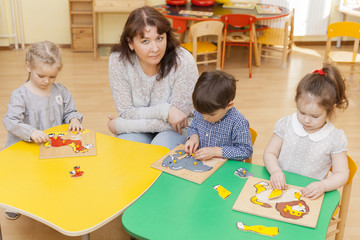 Fototapeta premium The teacher of preschool children with three students collect pu