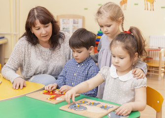 Fototapeta premium elementary school teacher collect puzzle with three pupils