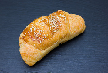 salty croissant with sesame on a slate floor