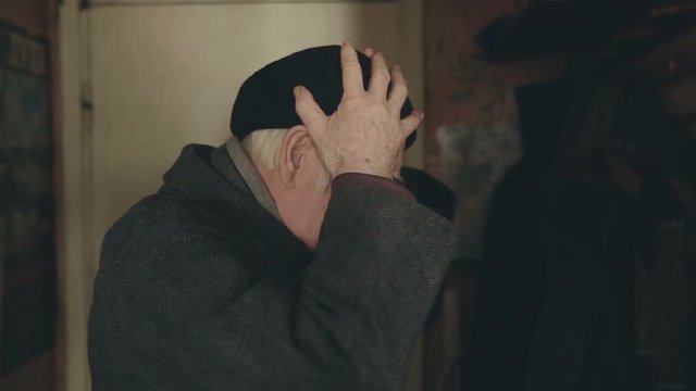 The elder man wearing the hat turns to a certain item and becomes frightened a bit.