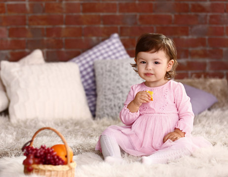 Little girl with fruit basket on the sofa