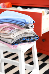 Stack of folded clothes on wooden stool closeup
