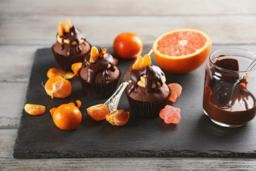 Tasty cupcake with fruits, chocolate and knife on slate plate over white wooden background