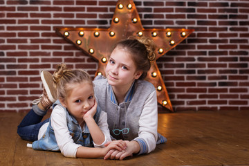 Two girls at home infront brick wall and decorative star