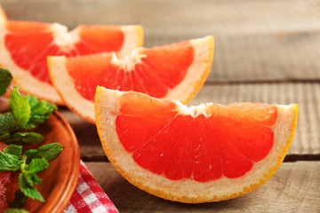 Juicy pieces of grapefruit with fresh mint on wooden table, close up