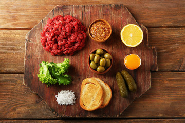 Beef tartare ingredients on wooden cutting board