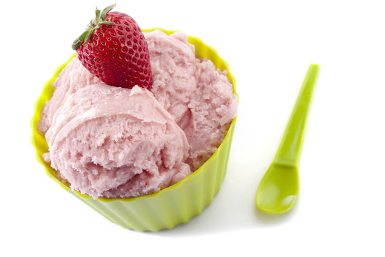 close up image of strawberry in green cup with green spoon