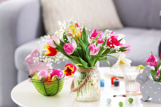 Bouquet of beautiful colorful tulips and Easter eggs on wooden table, indoors