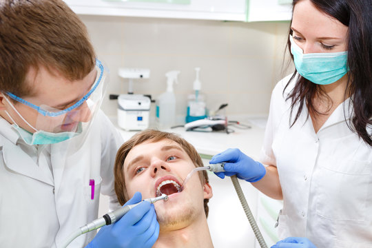 Dentist, assistant and the patient are ready for treating carious teeth