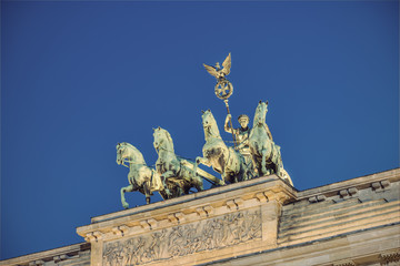 Obraz premium the bronze sculpture Quadriga on top of the Brandenburg Gate (Brandenburger Tor) at evening, Berlin, Germany, Europe, vintage filtered style 