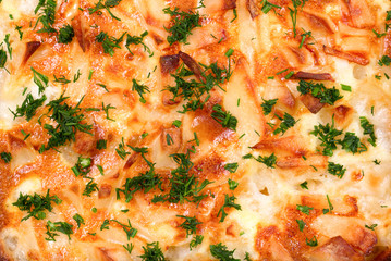 The ruddy slices of potatoes baked in sour cream with green