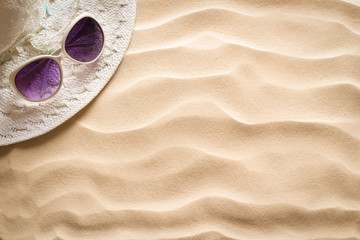 Straw hat and sunglasses on beach sand