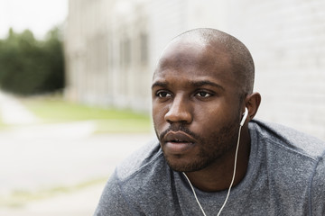 Black runner resting in city with earbuds